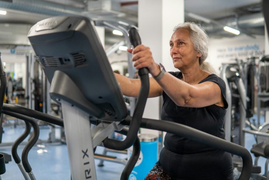 Mulher sénior a treinar numa máquina elíptica no ginásio