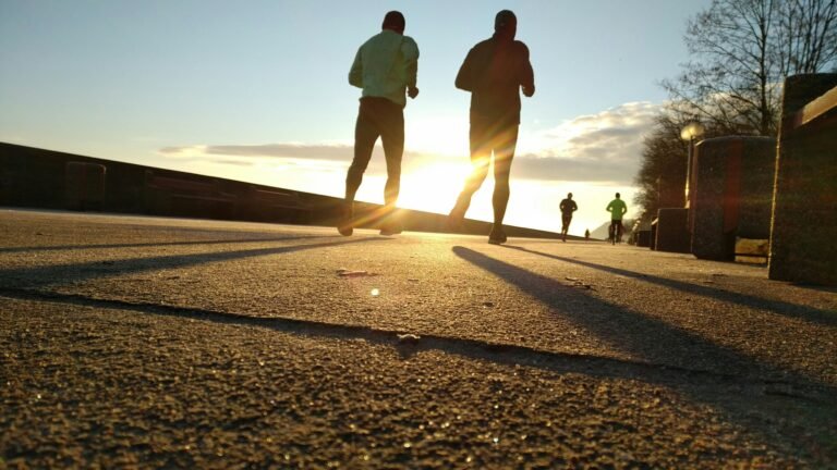 Duas pessoas a correr ao pôr do sol num passeio junto ao mar