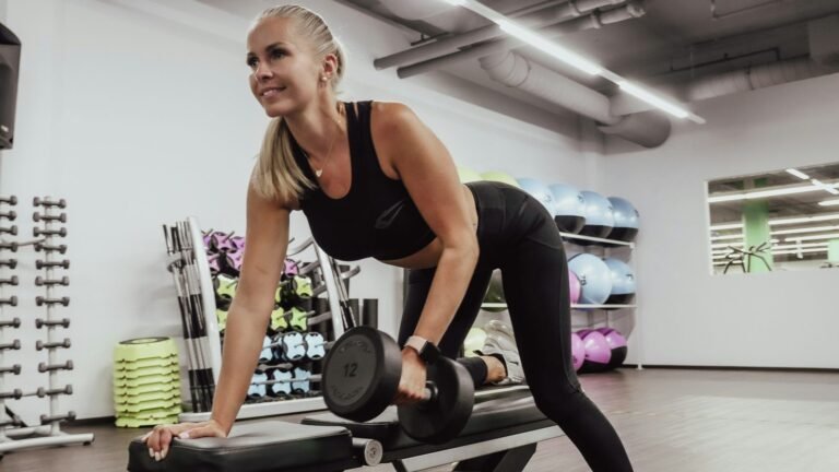 Mulher a fazer remada com haltere num ginásio, treino de força
