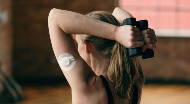 Mulher com sensor de glicose no braço a treinar com halteres