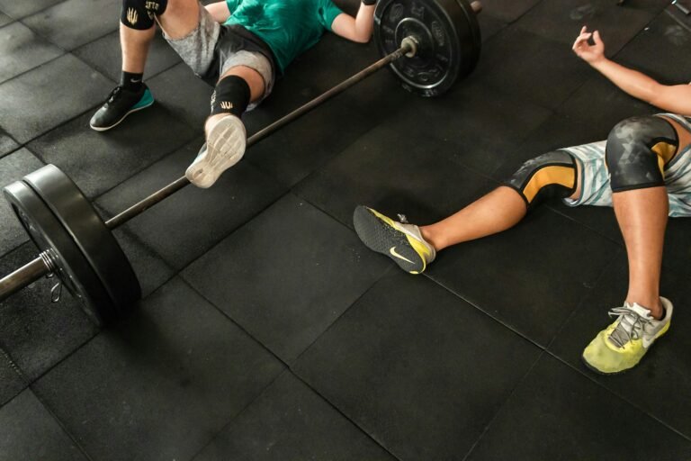 Pessoas a fazer exercícios de solo com barra num ginásio