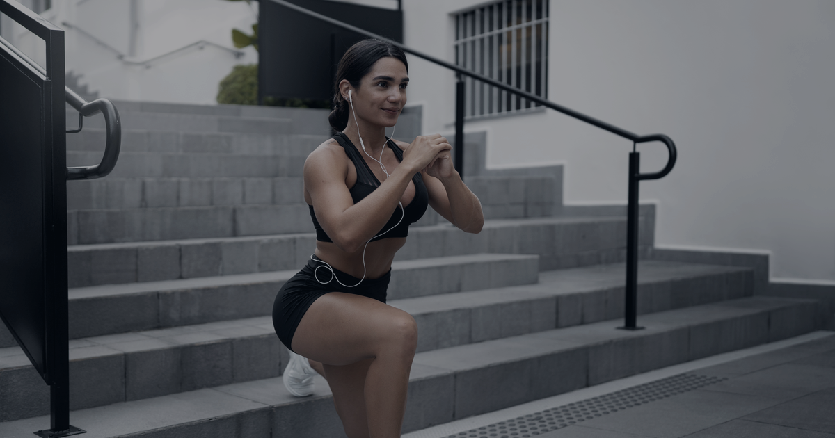 Mulher a treinar num agachamento em escadas exteriores