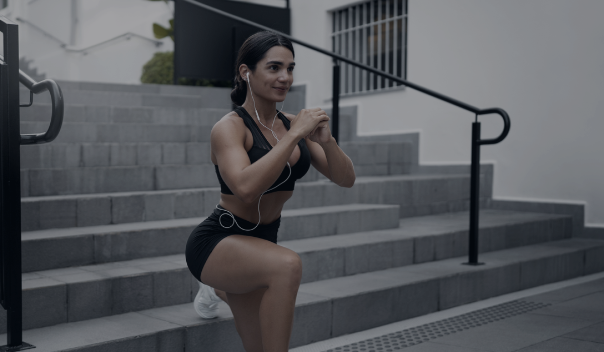 Mulher a treinar num agachamento em escadas exteriores