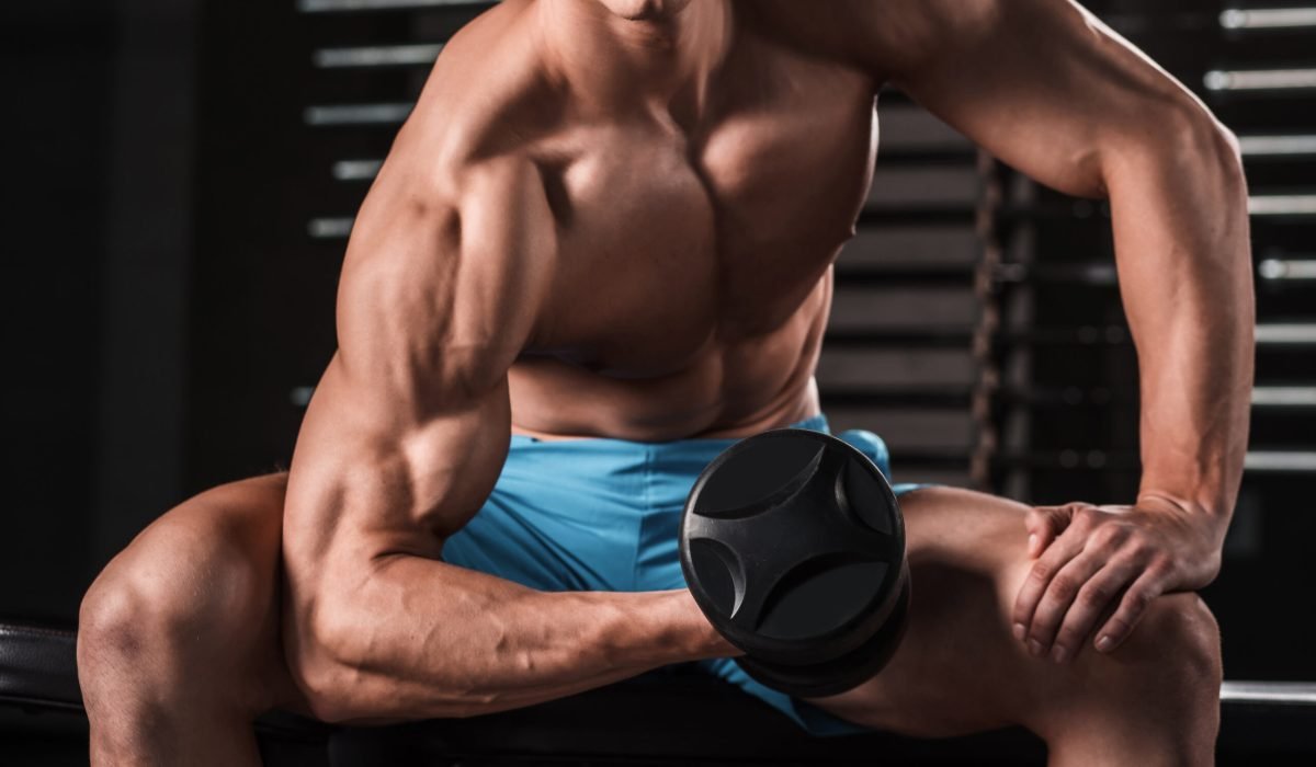 Very power athletic guy bodybuilder execute exercise with dumbbells at dark gym. Muscular man. Part of the body